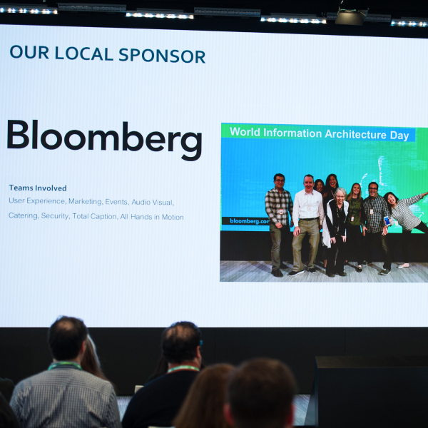 Screen showing the local sponsor, Bloomberg, and a photo of a group of people for World Information Architecture Day