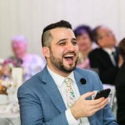 A picture of Majid laughing in a dining hall, wearing a blue suit