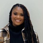 Profile photo of a black woman with long braids and a plaid jacket