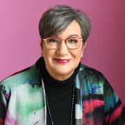 Photo of a white woman with short brown hair and red glasses