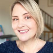 Profile photo of a white woman with short blond hair and black top