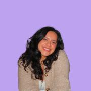 Profile photo of a hispanic woman with long curly hair, cream sweater on a purple background