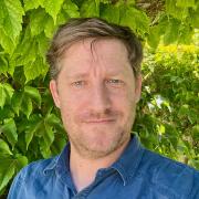 Male with light brown hair and blue buttoned shirt